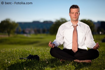 Barefoot businessman meditating in a beautiful park