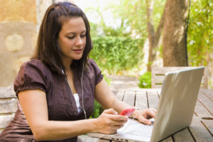 woman at computer with phone